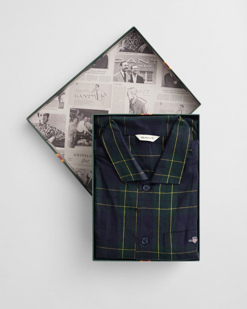 A folded navy blue plaid Pajama set by GANT is displayed inside an open branded gift box with a patterned interior, photographed on a clean light gray background.