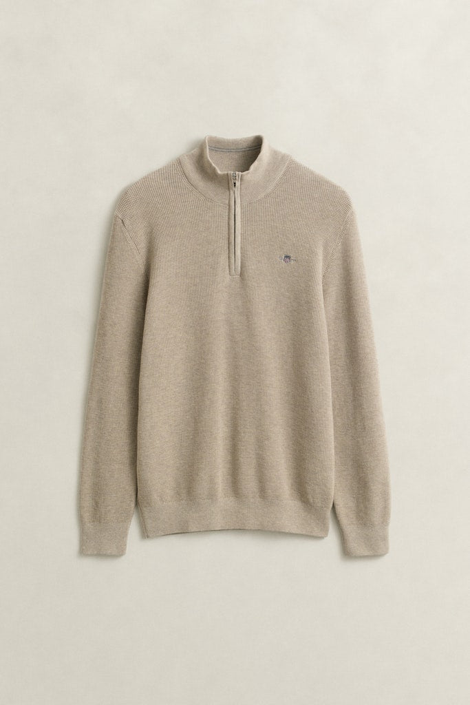 Beige sweater with a small Gant logo on a light beige background