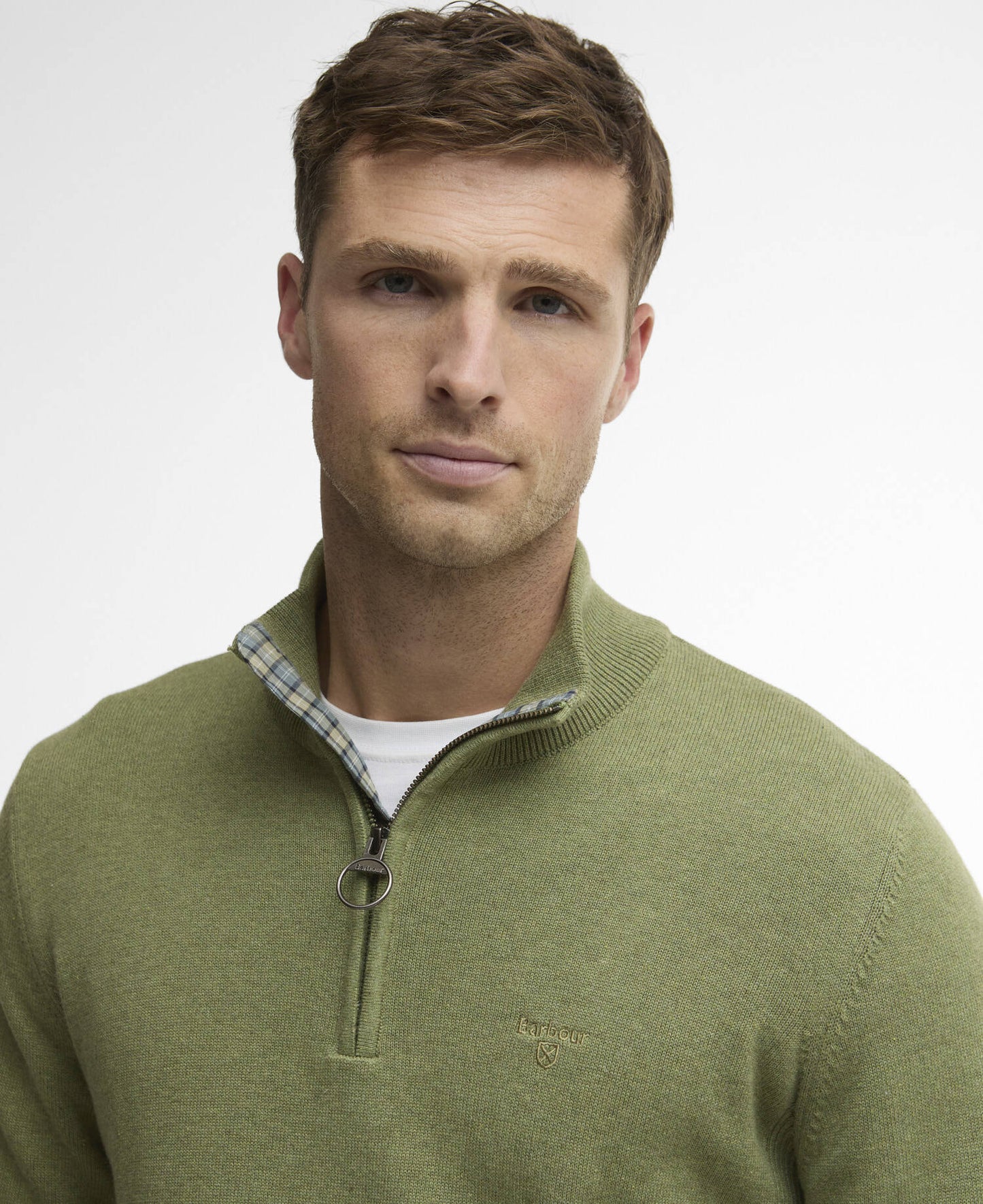 Man wearing a green sweater with a Barbour logo and quarter zip on a white background