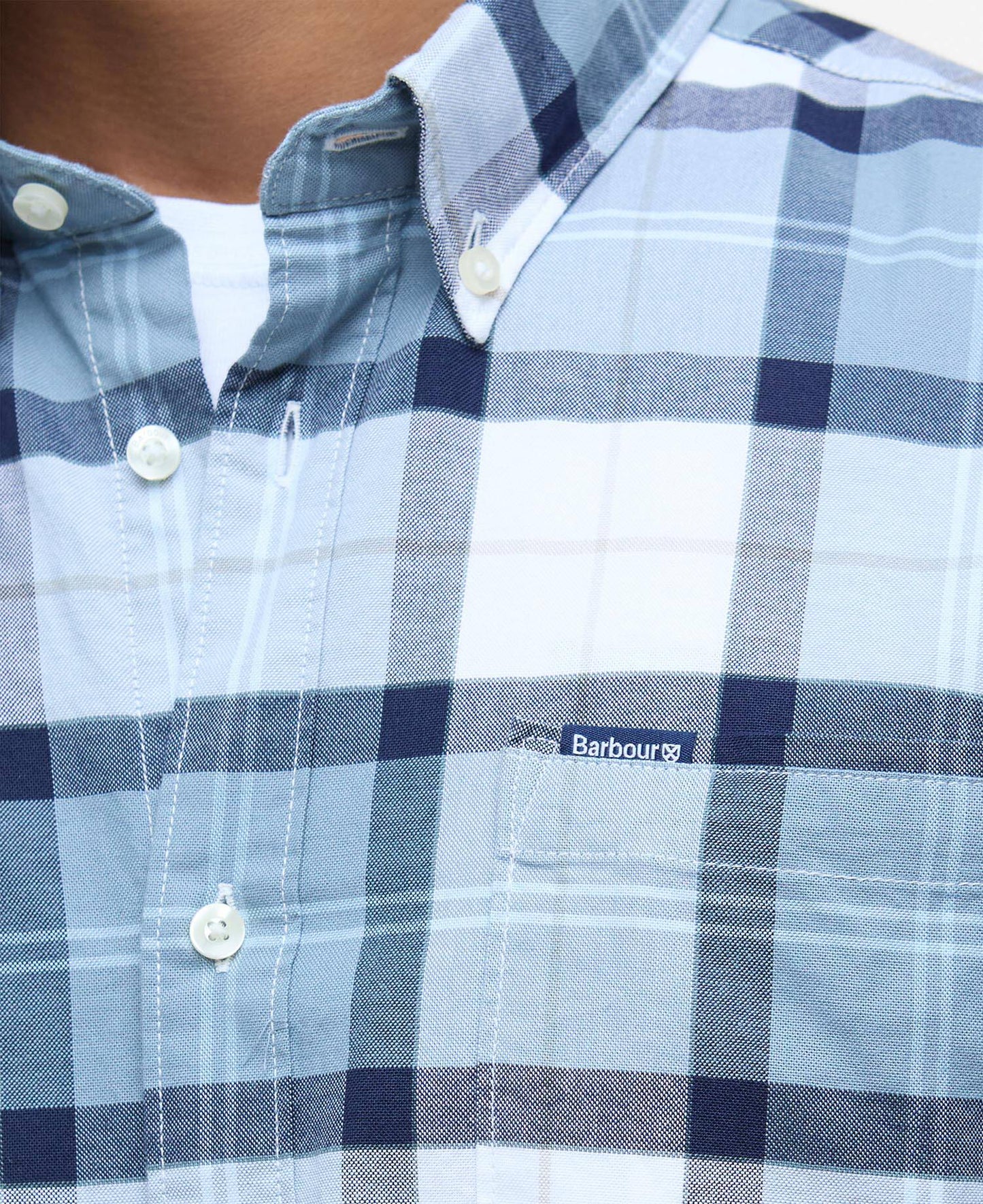 Close-up of a blue and white checkered shirt with Barbour logo.