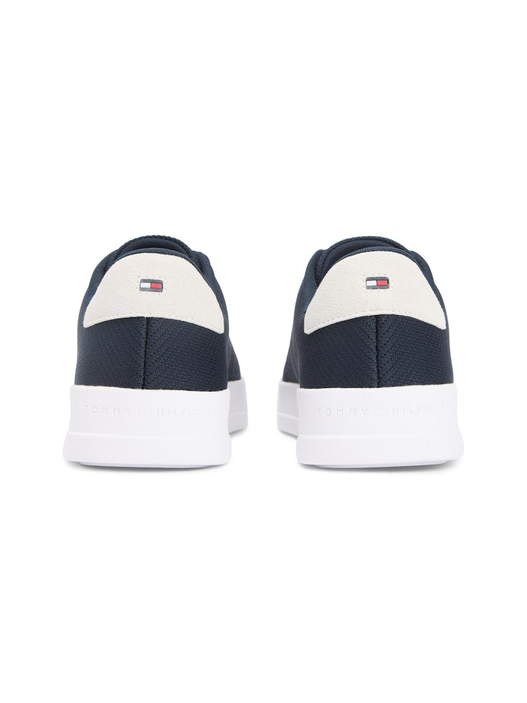 Heel view of dark blue sneakers with white sole unit. Tommy Hilfiger logo on the back