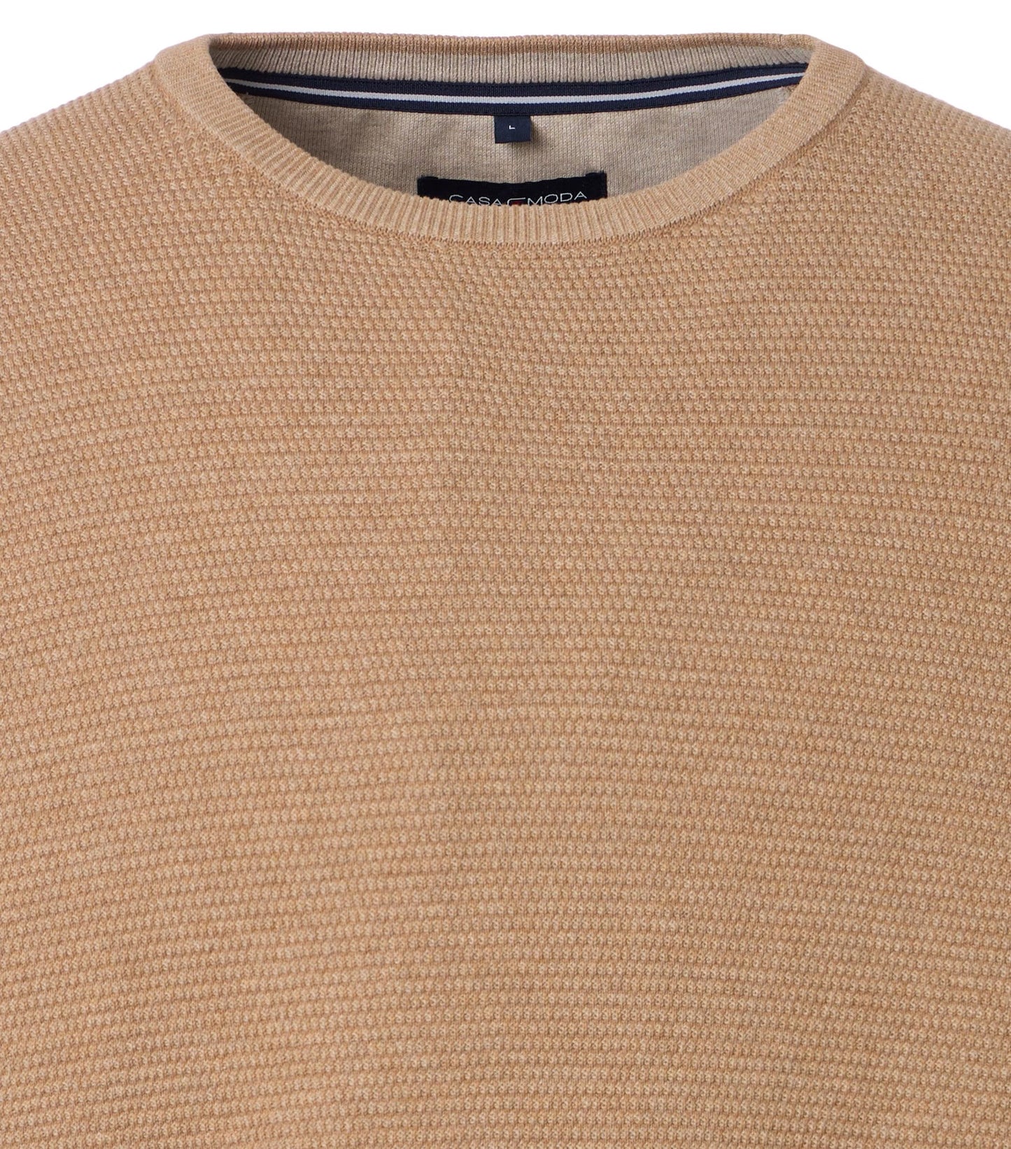 Close-up of a beige textured sweater with a brand label.