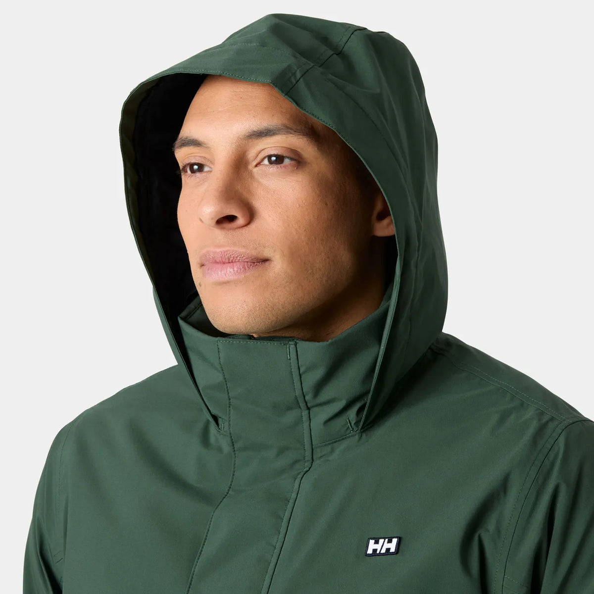 A man wearing a dark green hooded rain jacket with a high collar and a small white HH logo on the chest, shown against a light gray background.