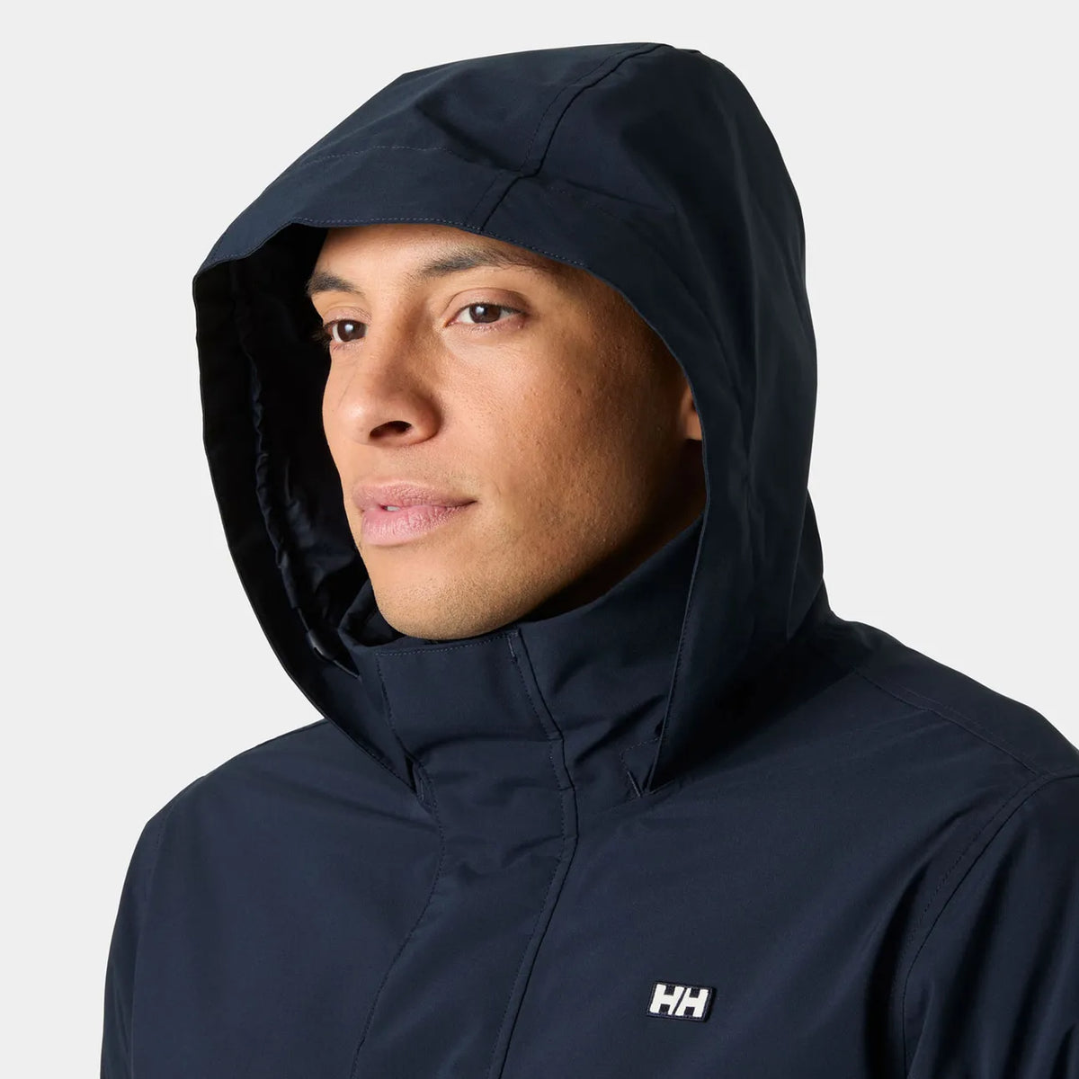 A man wearing a navy blue hooded jacket with a small white Helly Hansen 'HH' logo on the left chest, shown against a plain white background.