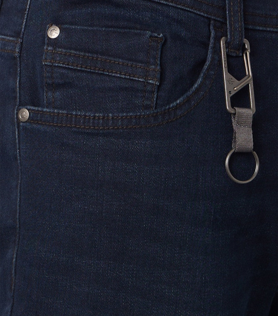 Close up of a side pocket of dark blue jeans including a small coin pocket and a silver keyring attached to the belt loop