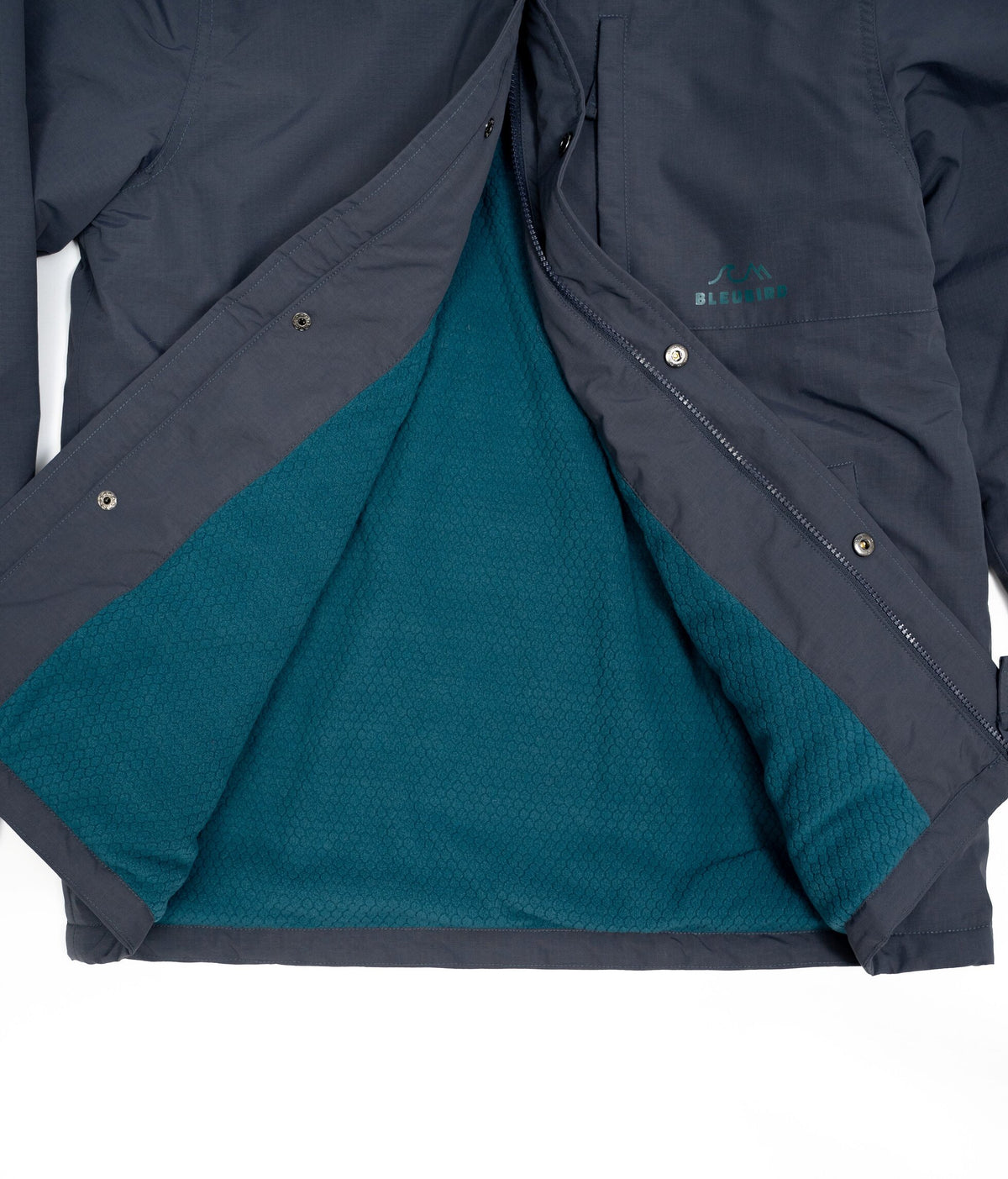 A close-up of a dark gray outdoor jacket with the front flap open to reveal a teal textured fleece lining. A small teal 'BLEUBIRD' logo is visible on the upper chest.