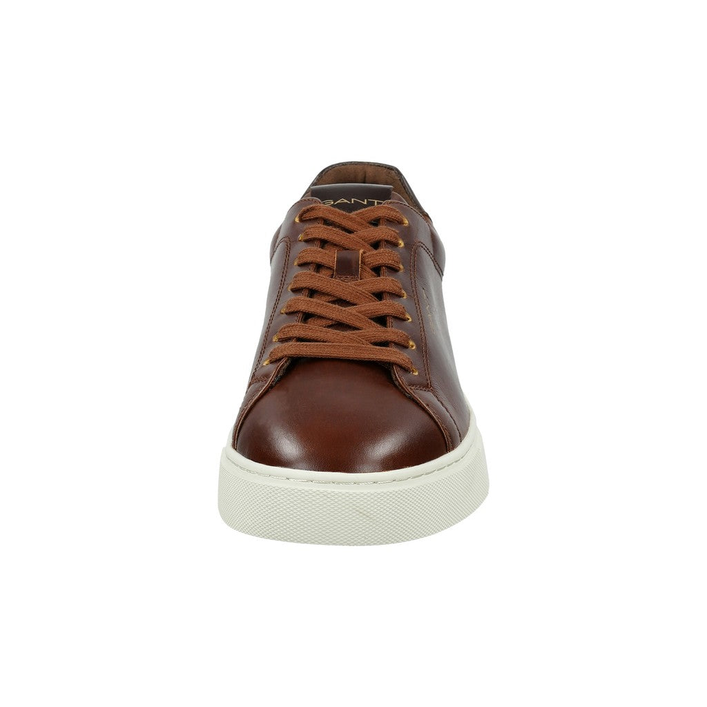A single brown leather low-top sneaker with matching brown laces and a thick white rubber sole, shown from a front-facing perspective on a solid white background.