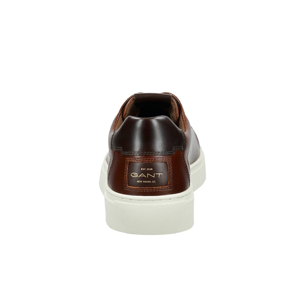A single brown leather low-top sneaker shown from the back, featuring a dark brown heel tab with a gold GANT logo and a thick white platform sole.