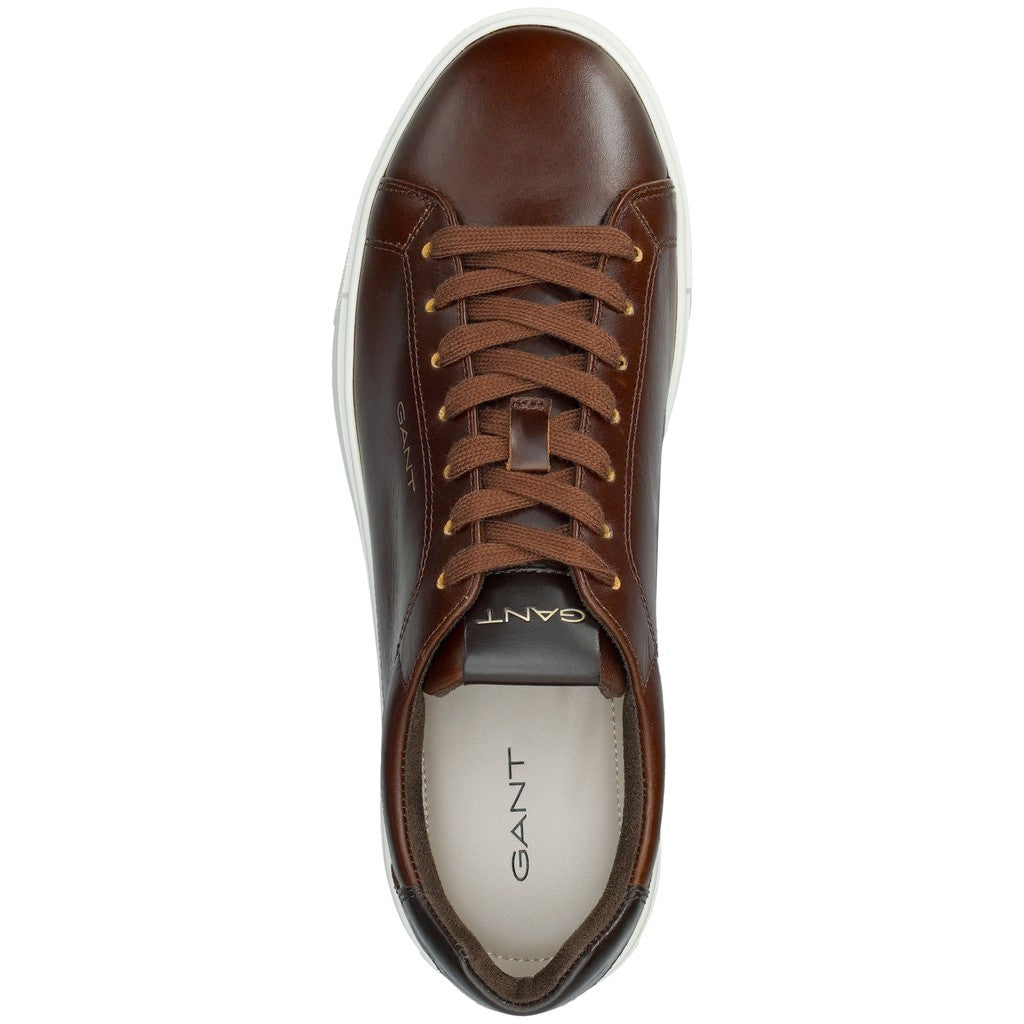 A single brown leather sneaker shown from a top-down view on a white background, featuring matching brown laces, a dark brown tongue with gold GANT lettering, and a white midsole.