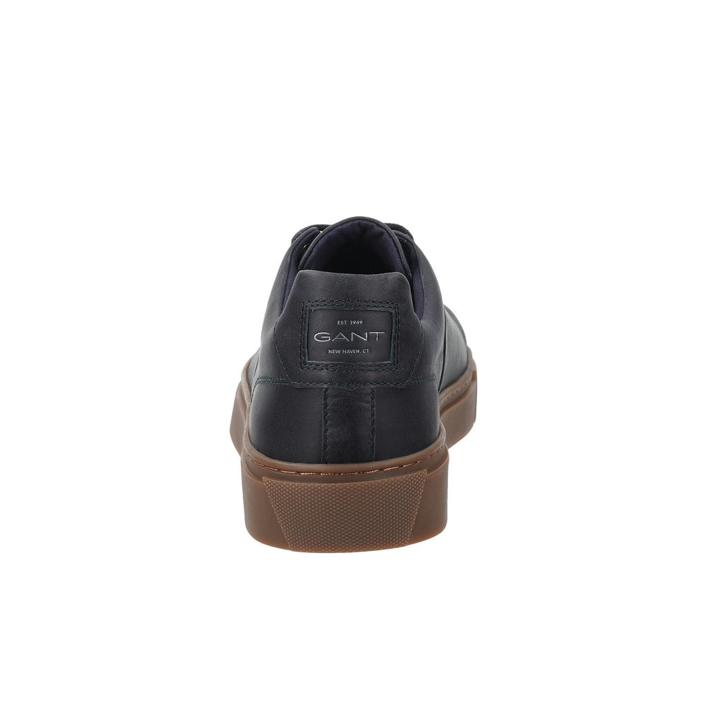A single GANT sneaker shown from the rear, featuring a dark navy blue leather upper and a brown gum sole, set against a plain white background.