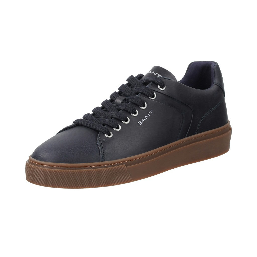 A GANT low-top sneaker in dark navy blue leather with a brown gum sole, featuring navy laces and silver eyelets, shown from a three-quarters angle on a white background.