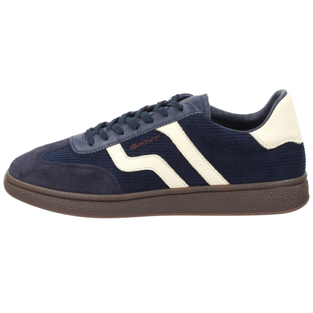 A navy blue suede and corduroy sneaker with white side stripes, a white heel tab, and a brown textured rubber sole, shown in a side profile on a white background.
