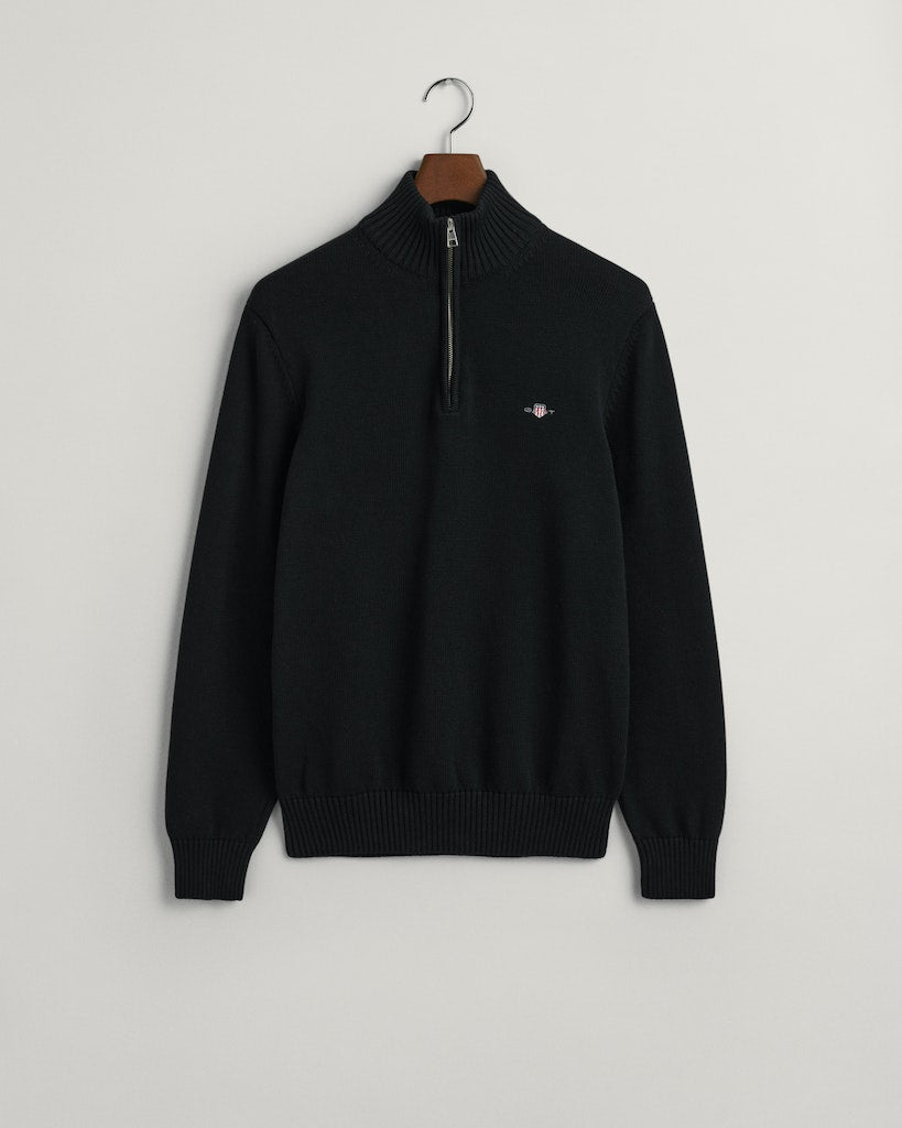 Black sweater with a small GANT logo on a hanger against a light gray background