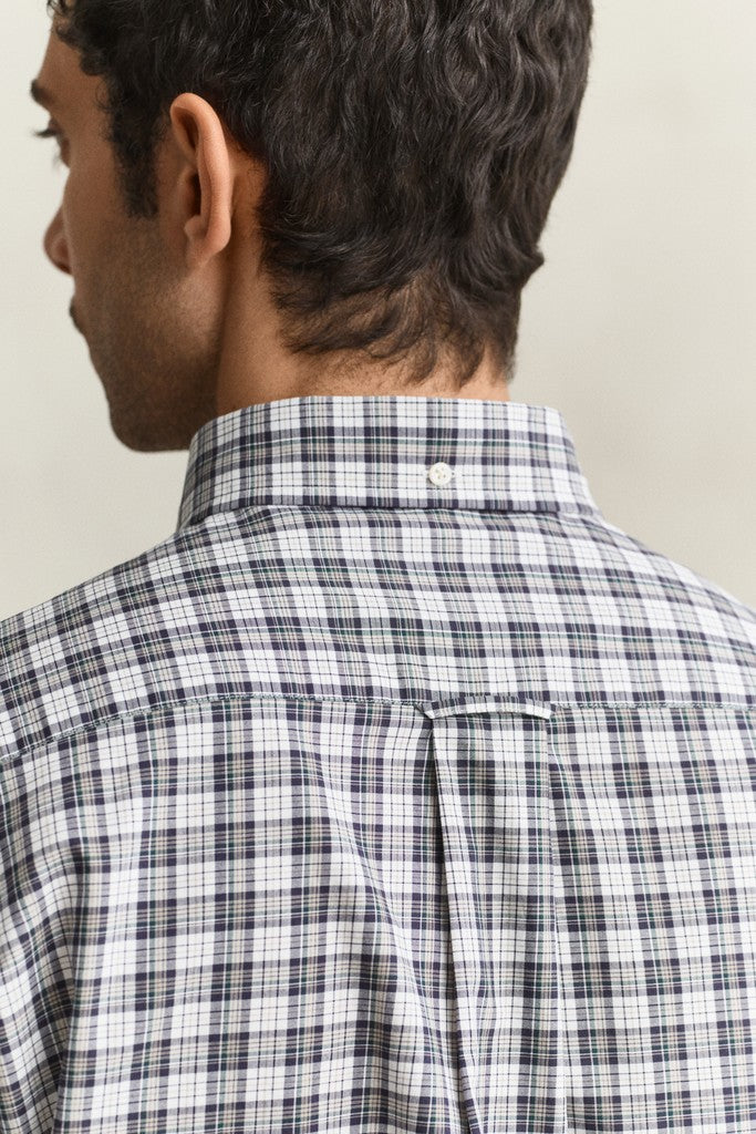 Close-up back view of a man wearing a white plaid button-down shirt with black and gray lines, showing the collar and upper back against a light beige background.