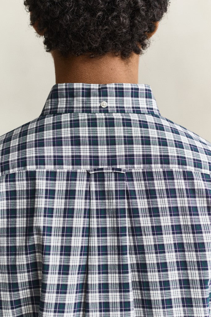 Back view of a person wearing a navy, white, and gray plaid button-down shirt, showing the collar and upper back against a plain light background.