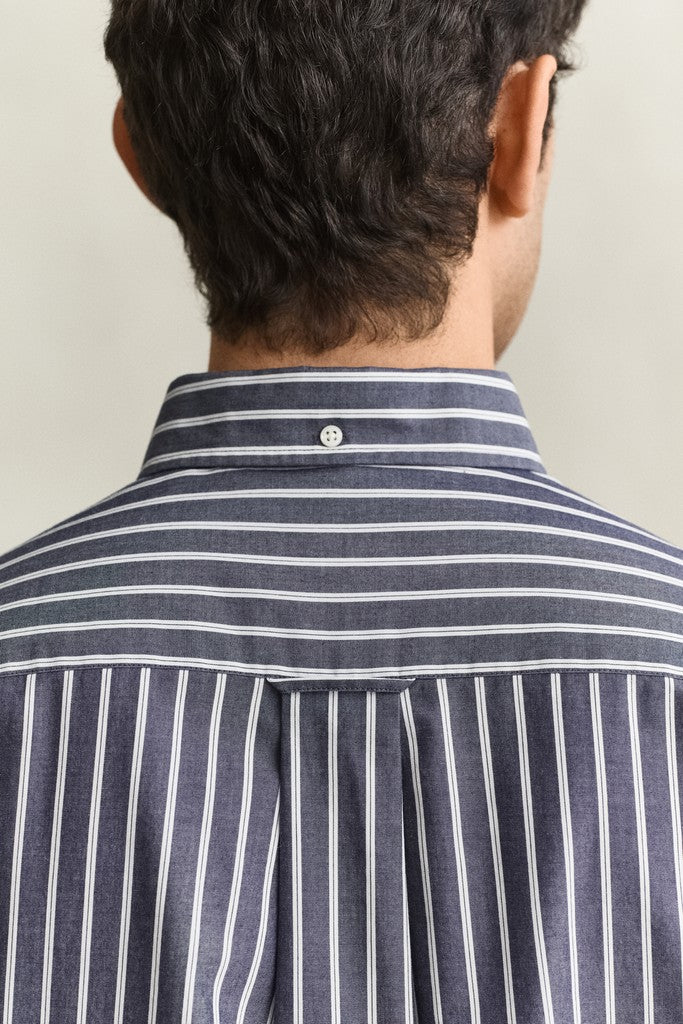 Close-up back view of a man wearing a navy and white striped button-down shirt, showing the collar, button, and vertical stripe pattern on the shoulders and upper back.