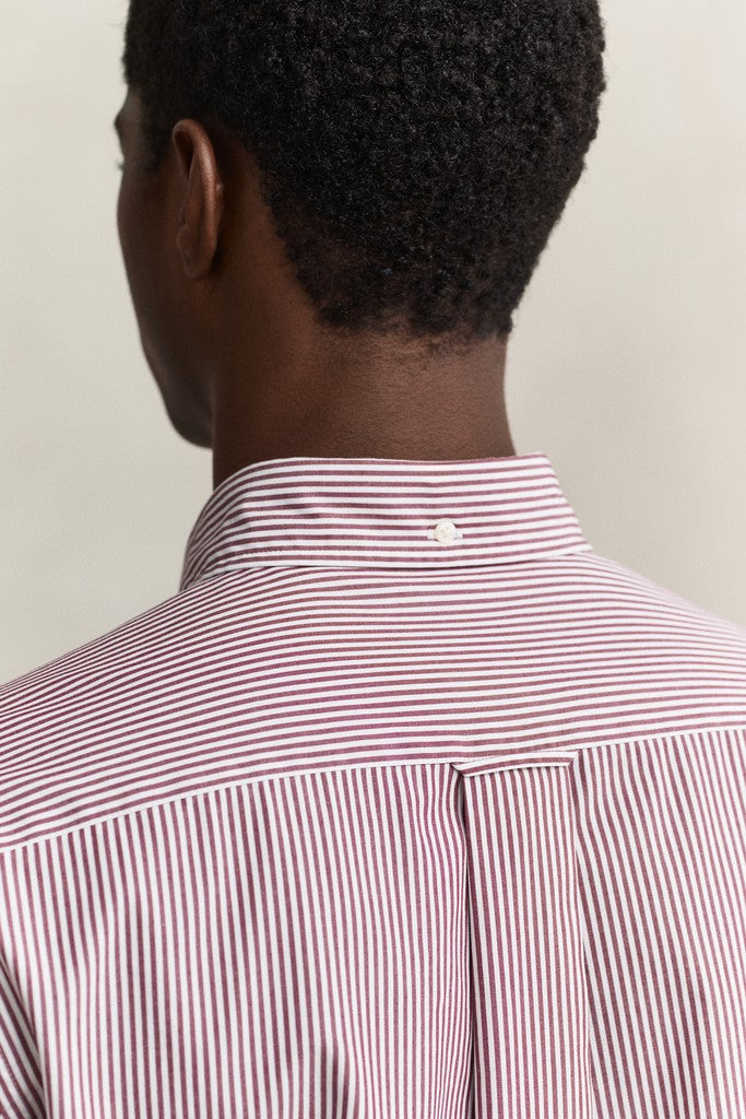 Close-up back view of a man wearing a red and white striped button-down shirt, showing the collar and upper back against a plain light background.