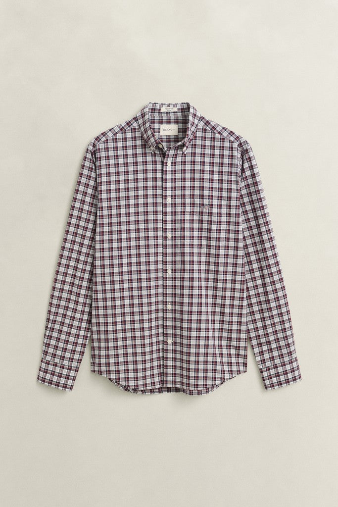 A long-sleeve button-down shirt with a small-scale plaid pattern in dark red and black, laid flat against a light beige background.
