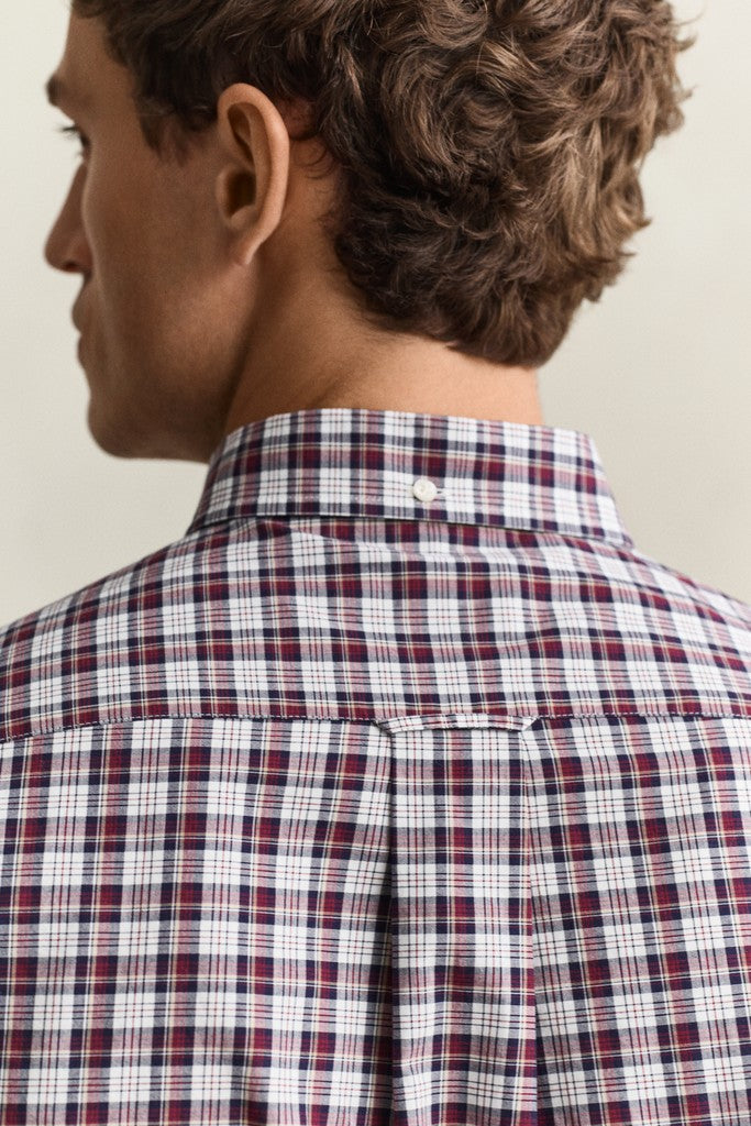 Close-up back view of a man wearing a red, white, and navy plaid button-down shirt.