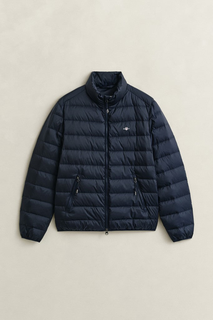 A dark navy blue puffer jacket with horizontal quilting, a stand-up collar, and a front zipper, laid flat against a light beige background.