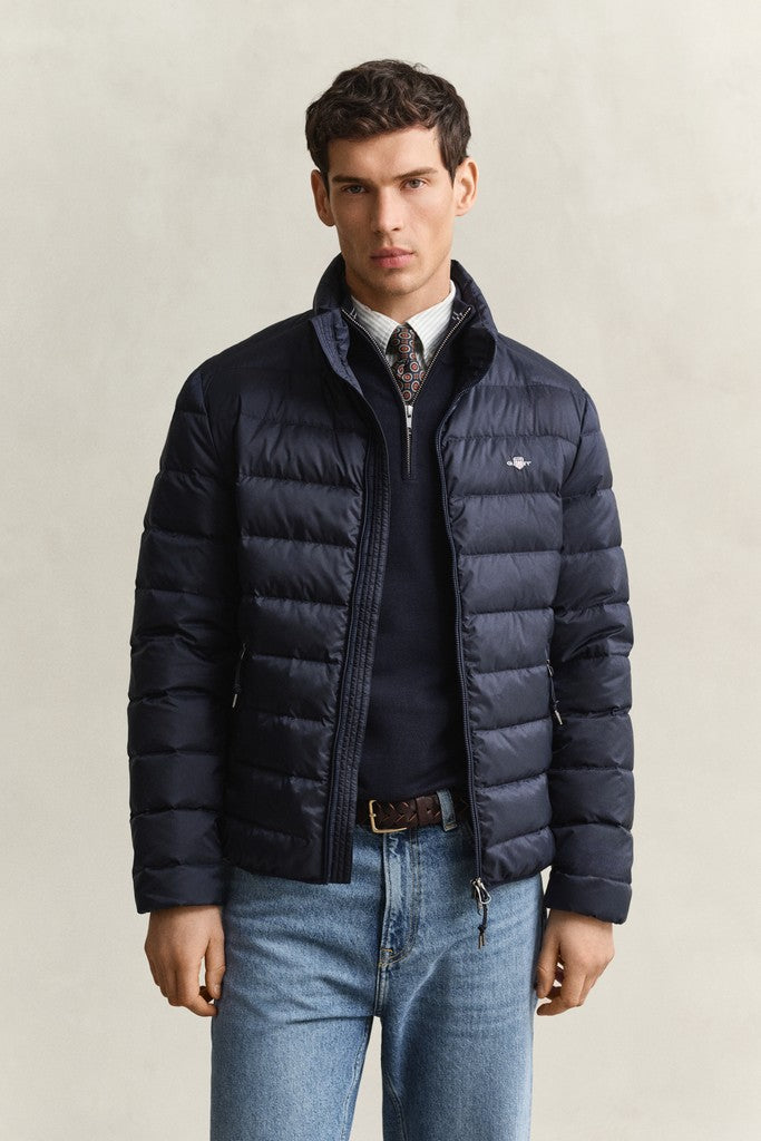 Man wearing a navy blue GANT puffer jacket over a navy quarter zip sweater and blue jeans