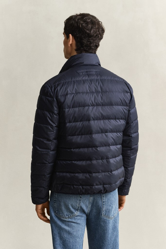 Back view of a an wearing a navy blue GANT puffer jacket over blue jeans