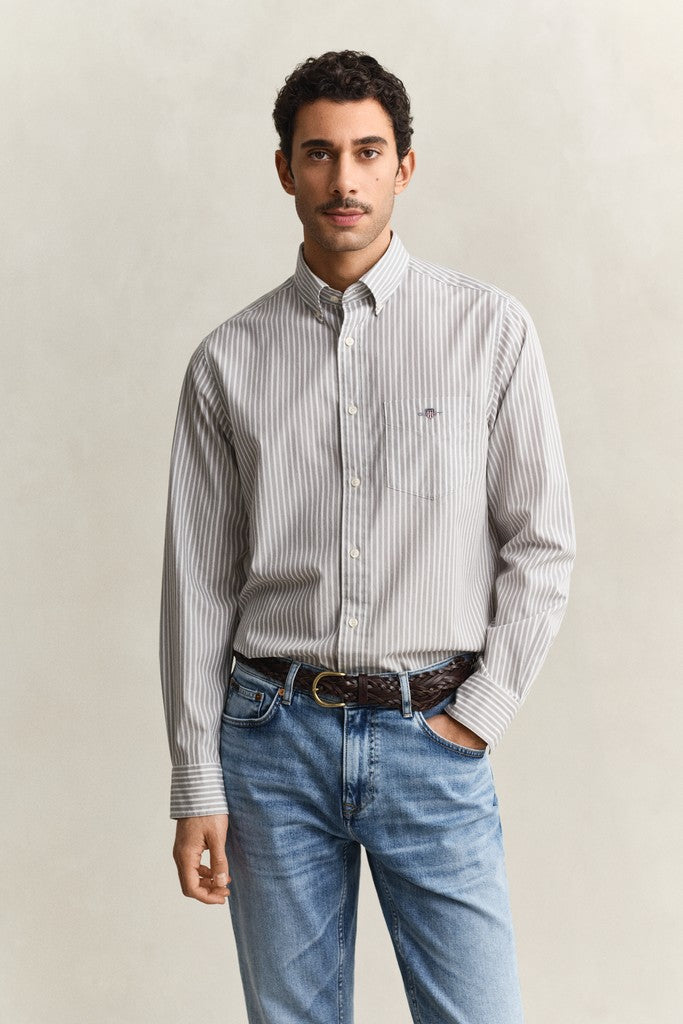 Man wearing a striped shirt and jeans against a plain background