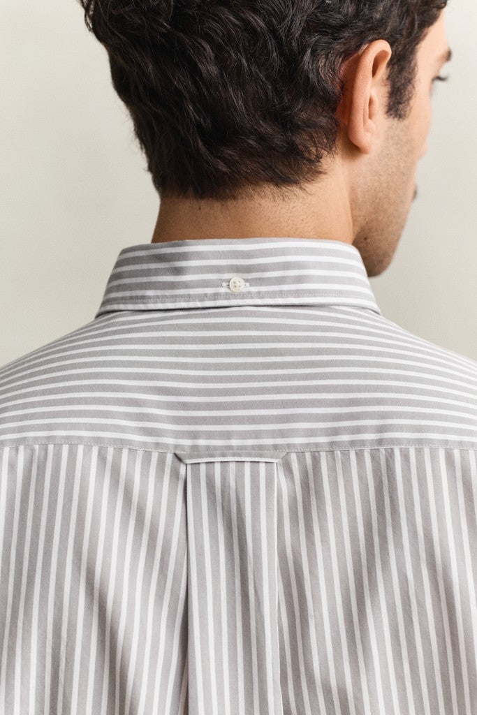 Man wearing a gray and white striped shirt with a neutral background