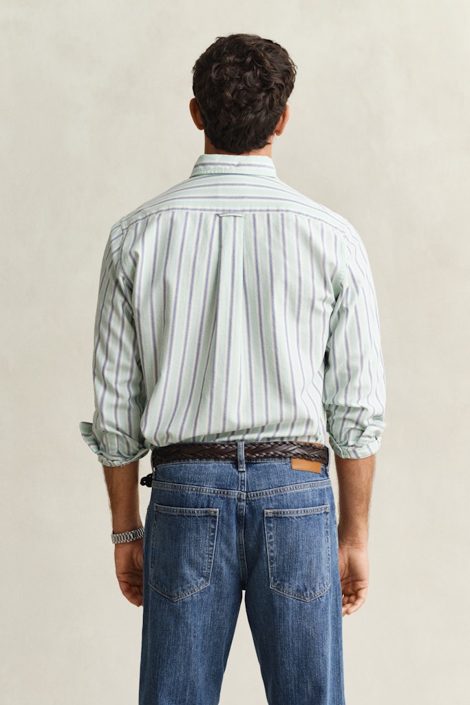 Man wearing a striped shirt and blue jeans against a plain background