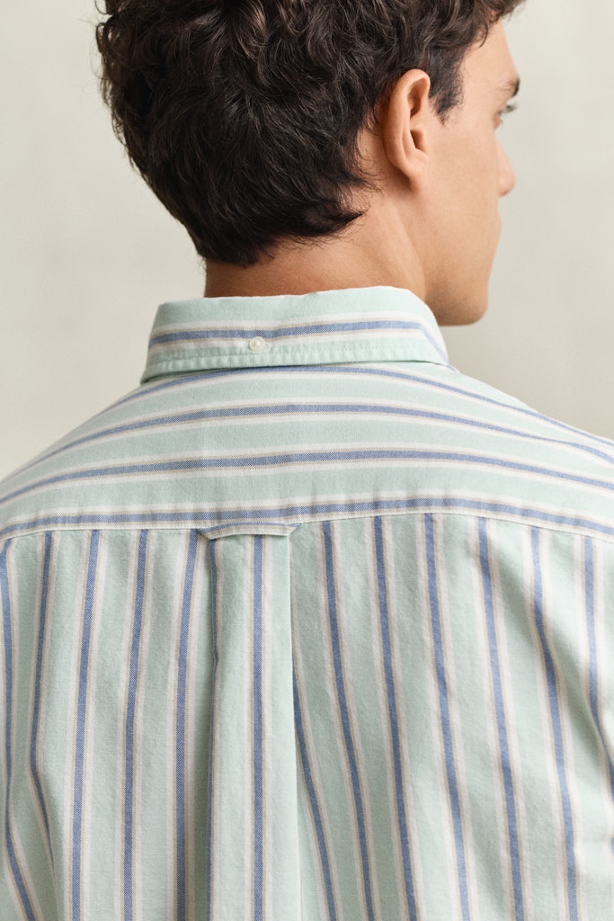 Man wearing a light green and blue striped shirt against a neutral background