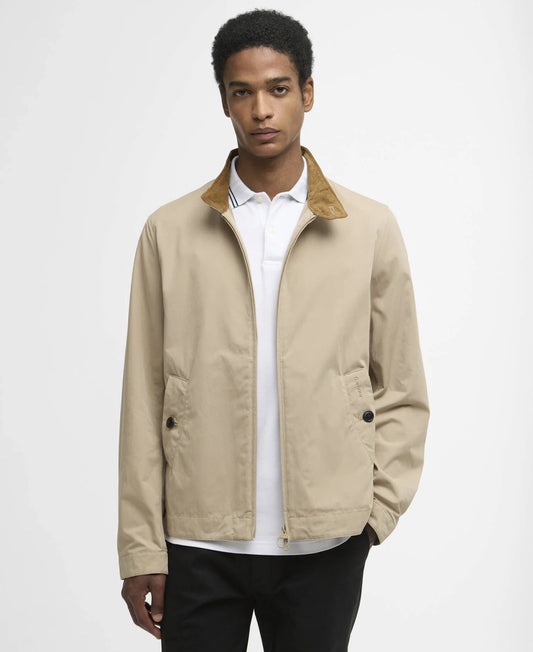 Man wearing a beige jacket over a white shirt on a plain background