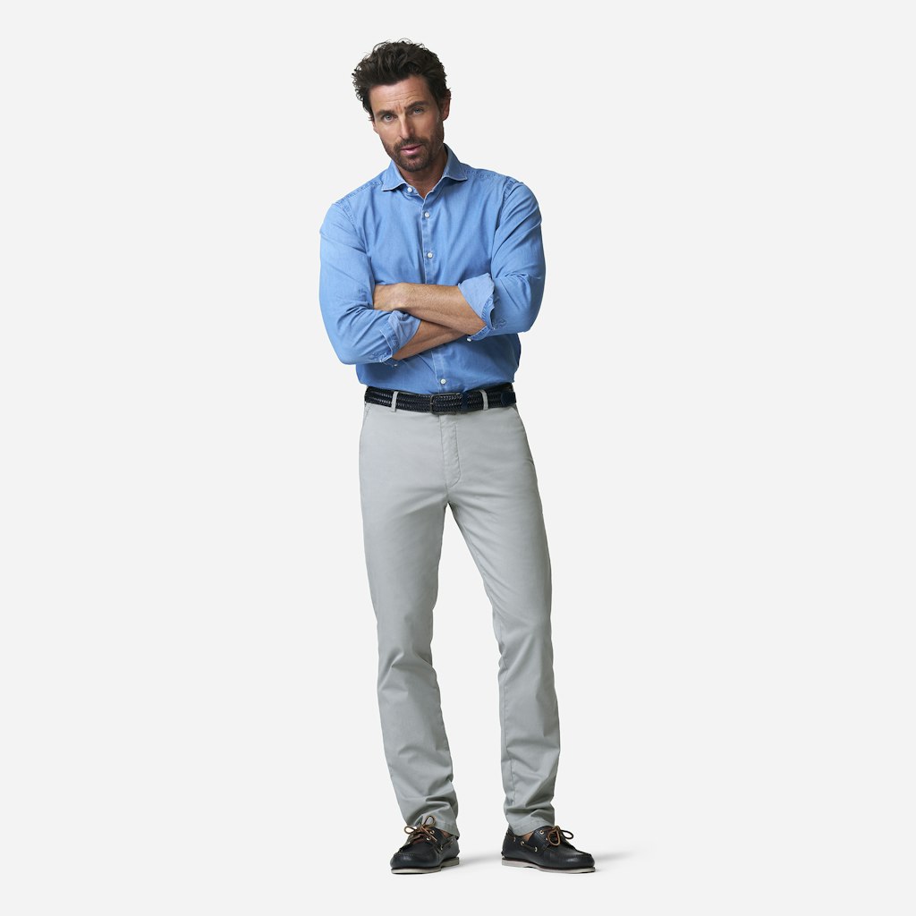 Man wearing a blue shirt and gray pants on a white background