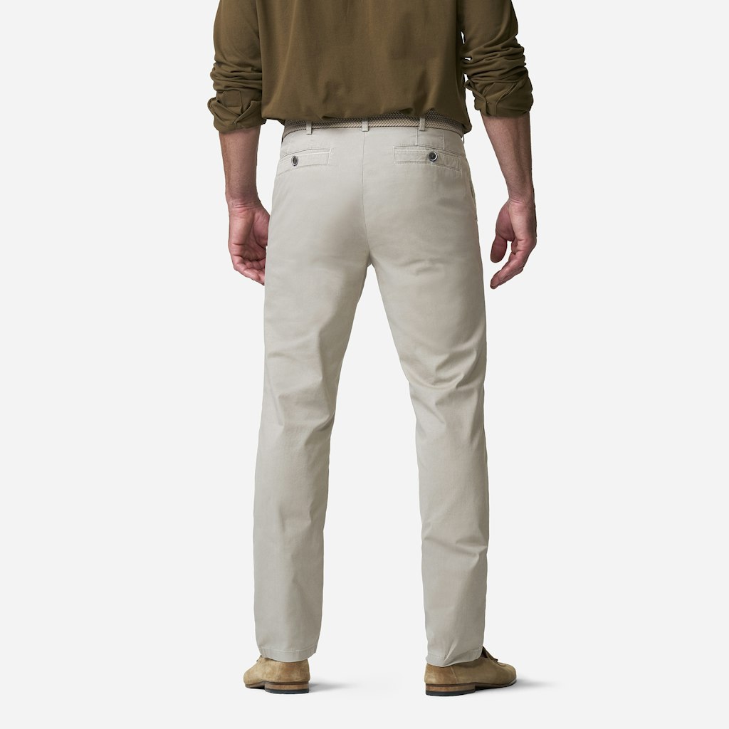 Person wearing beige pants and a brown shirt on a white background