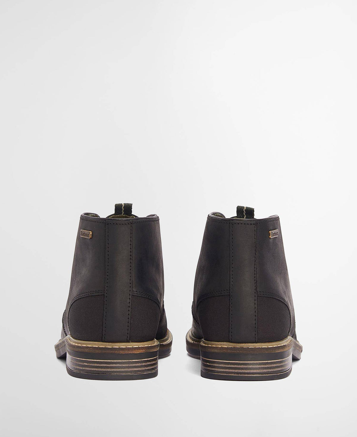 A pair of black leather ankle boots shown from the back, featuring stacked brown and beige soles, set against a plain light gray background.