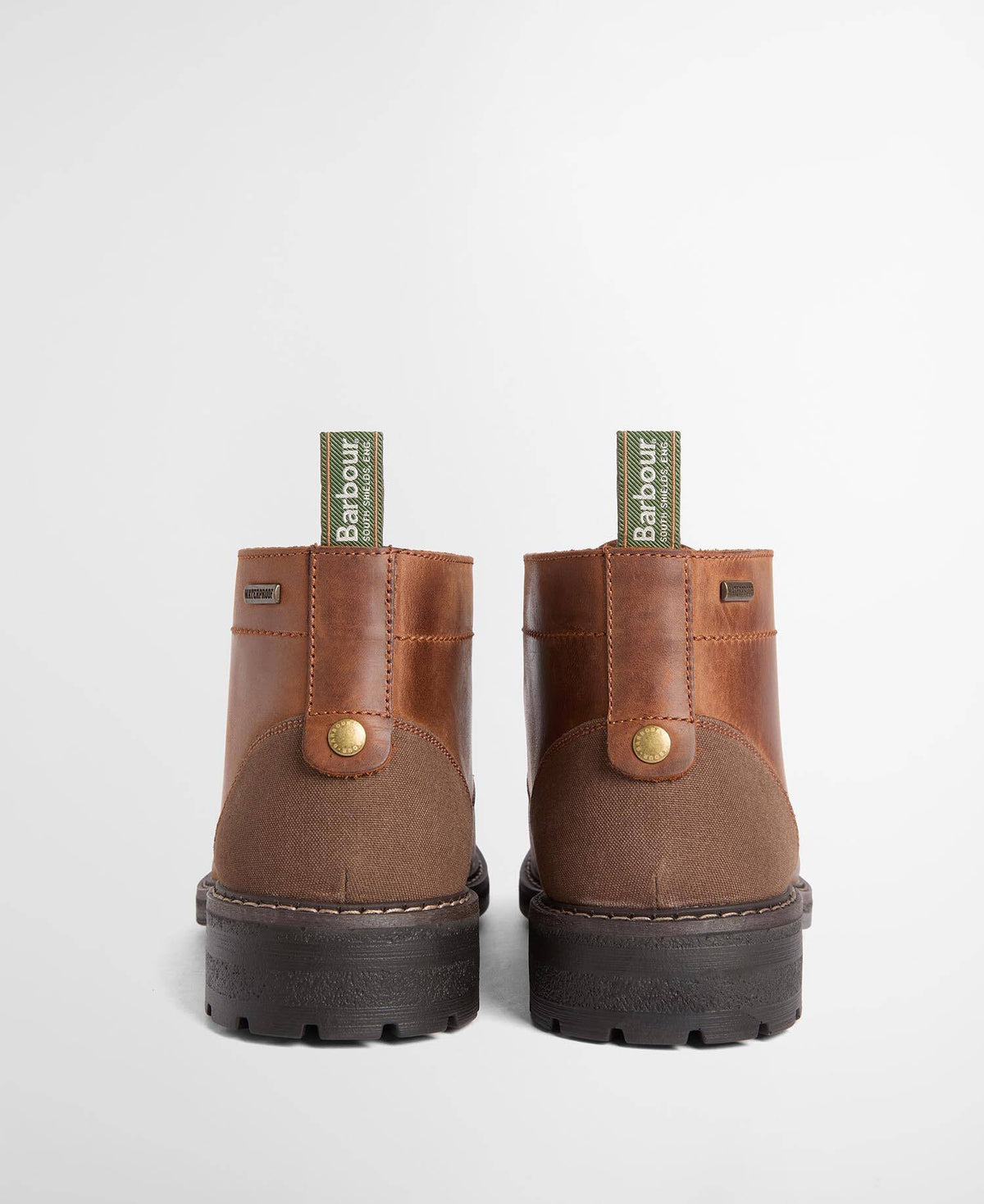 A pair of Barbour boots shown from the back, featuring brown leather and suede uppers with a dark brown lug sole and a green Barbour pull tab.