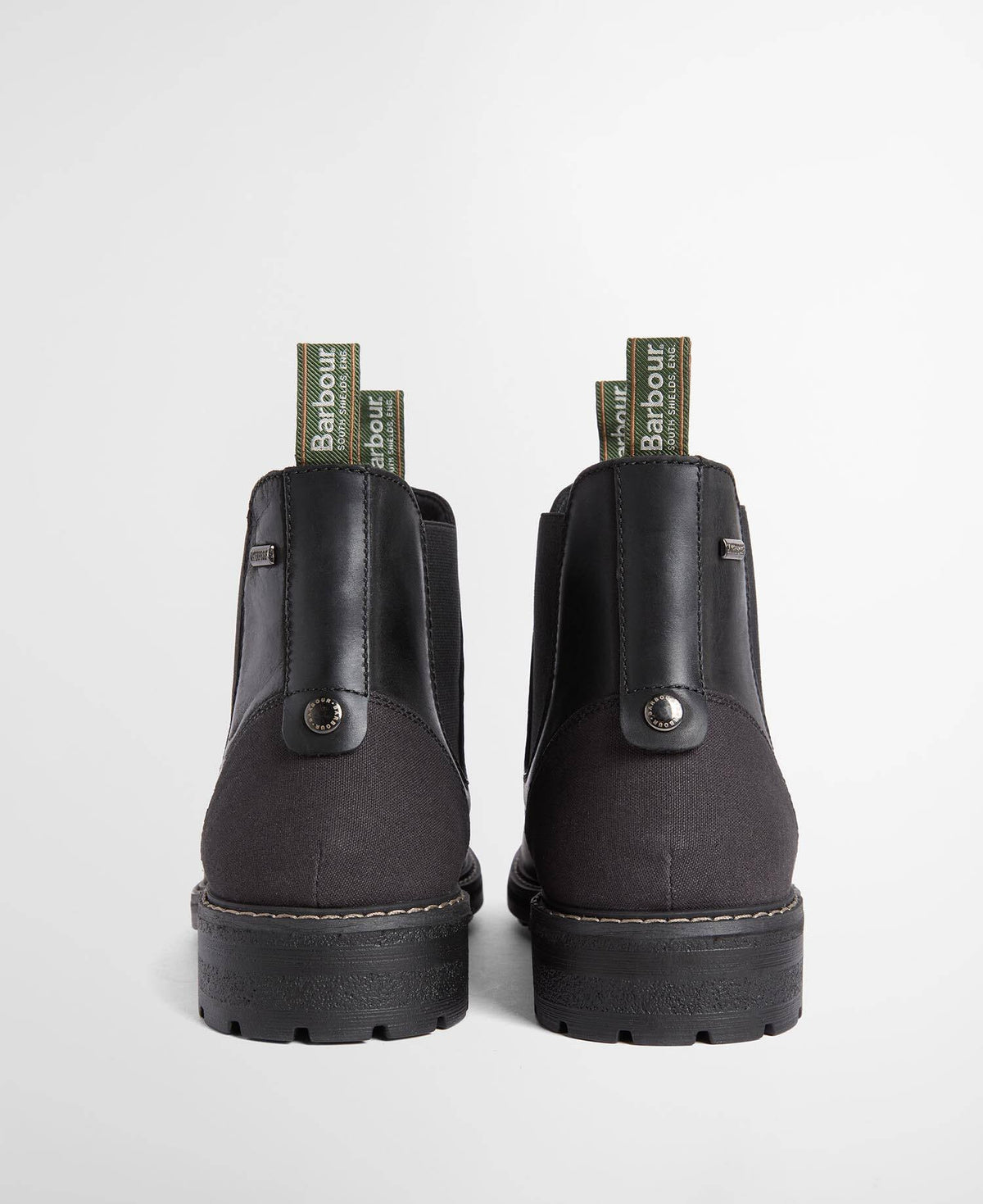 A pair of black leather Chelsea boots shown from the back, featuring green Barbour brand pull tabs and dark soles, set against a light gray background.
