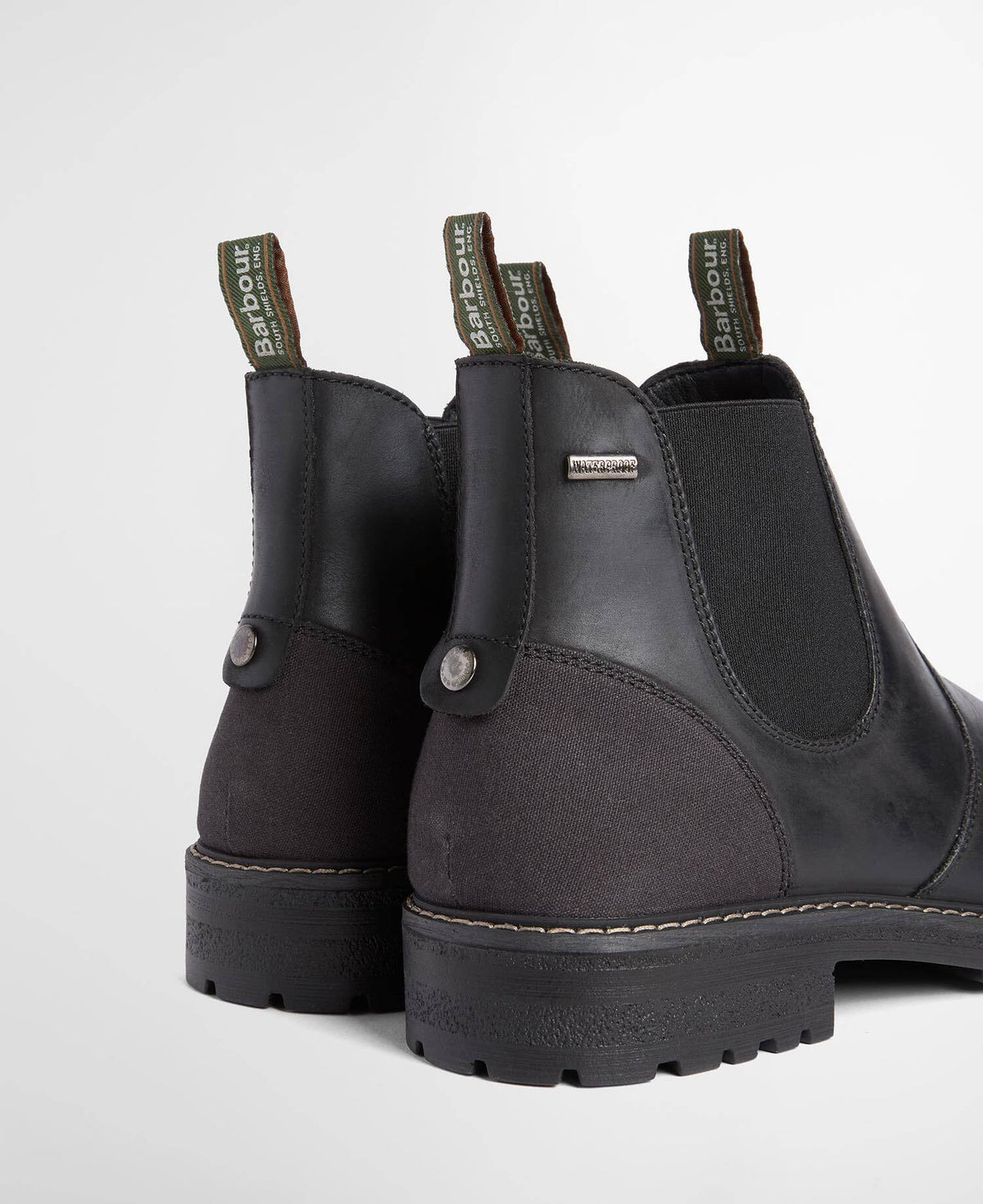 A pair of Barbour Chelsea boots in black leather and dark gray suede, shown from the back on a light gray background.