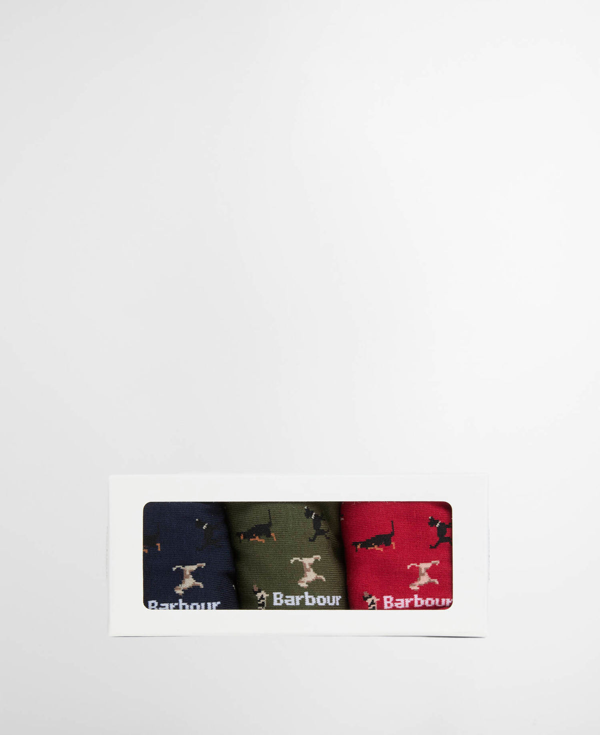 A white rectangular gift box with a clear window displaying a set of three Barbour socks in navy, olive green, and red, each featuring the iconic black dachshund dog logo and white Barbour branding.