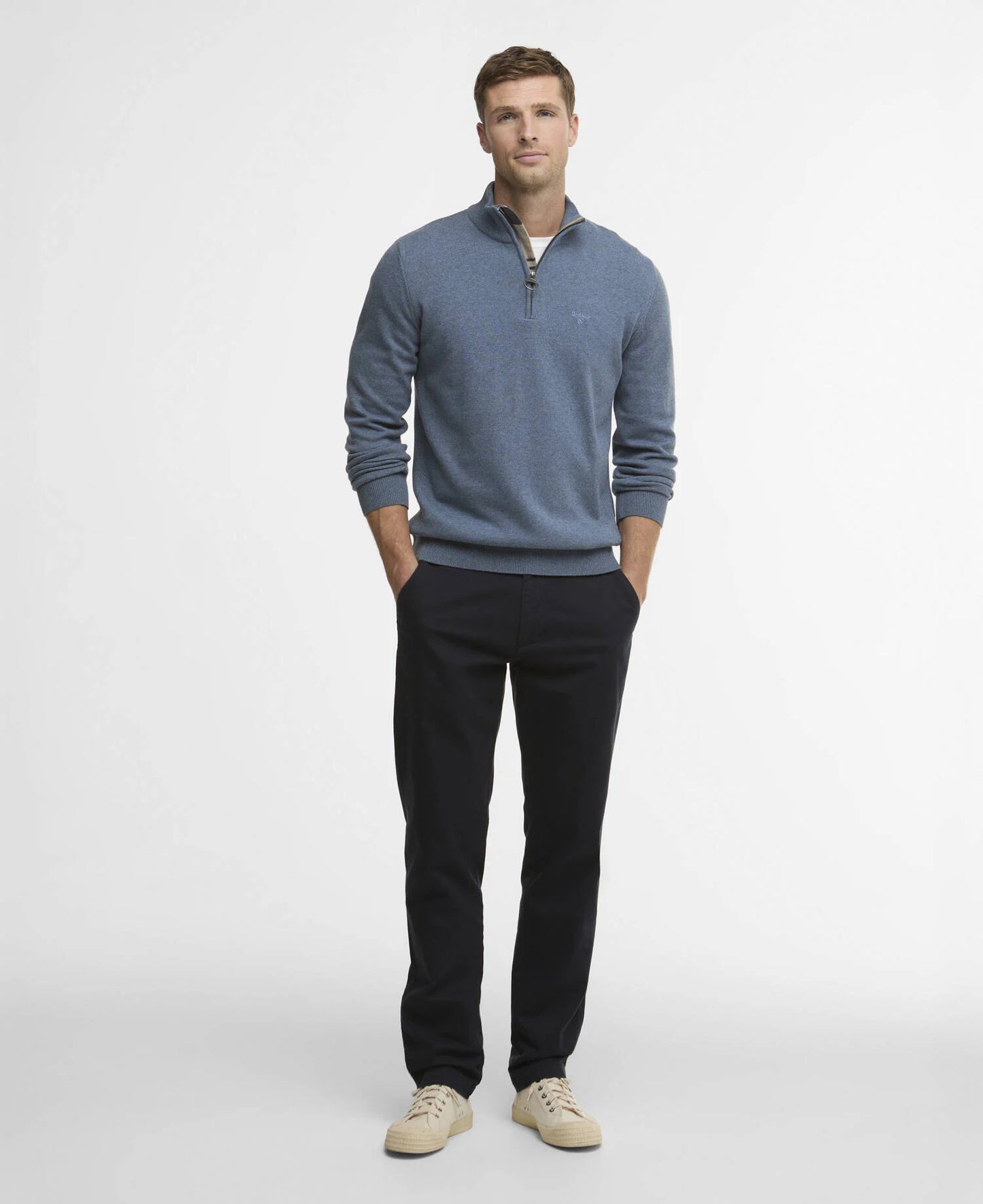 Man wearing a blue sweater and black pants on a white background