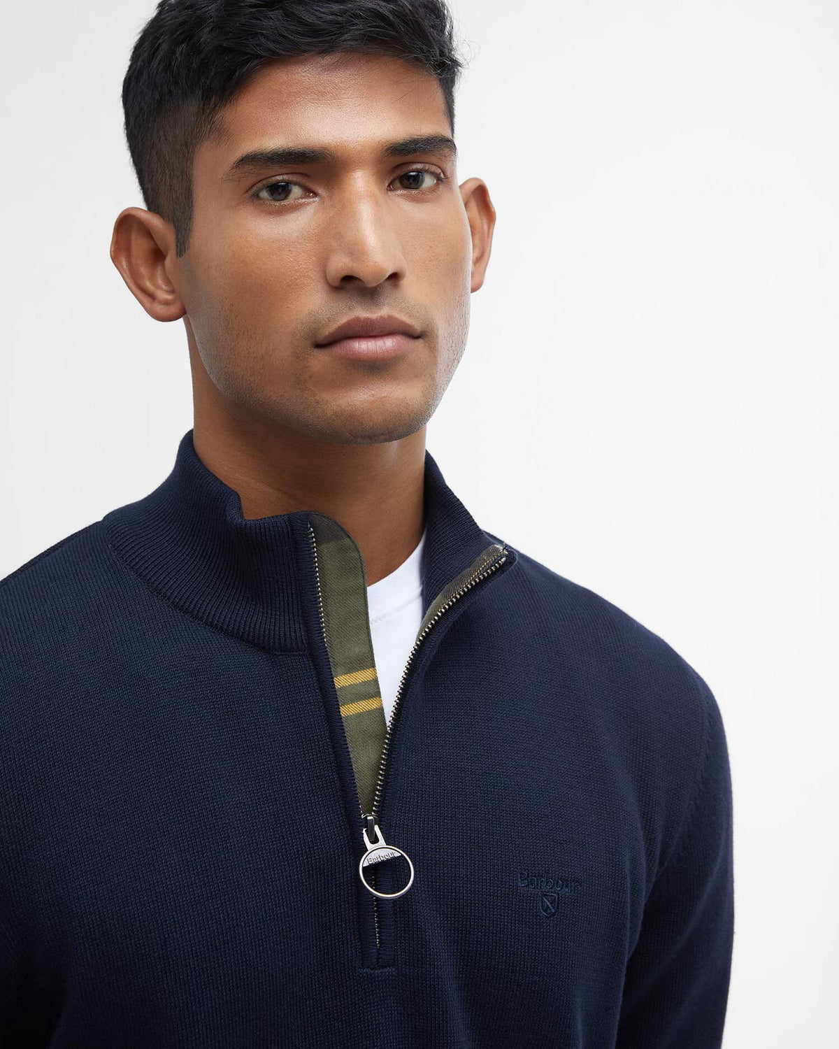 Man wearing a navy blue zip-up sweater against a white background