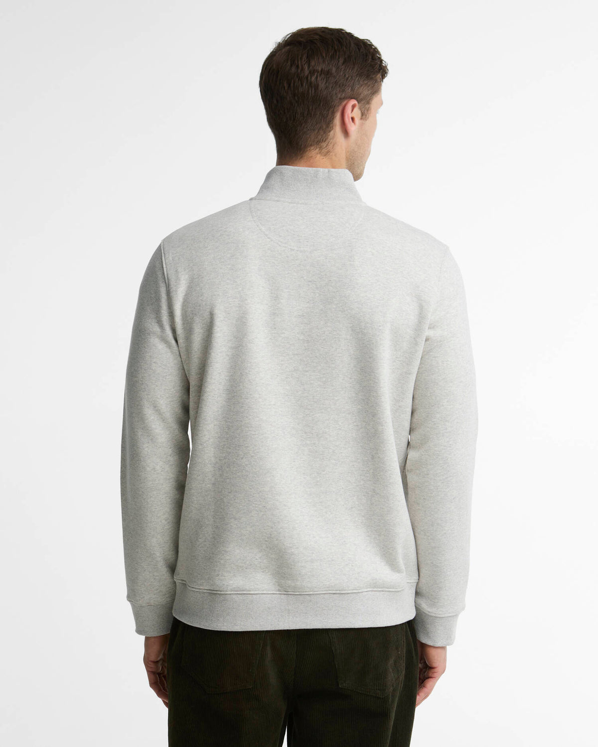 A man viewed from the back wearing a light gray heathered quarter-zip sweatshirt and dark trousers, set against a plain white studio background.