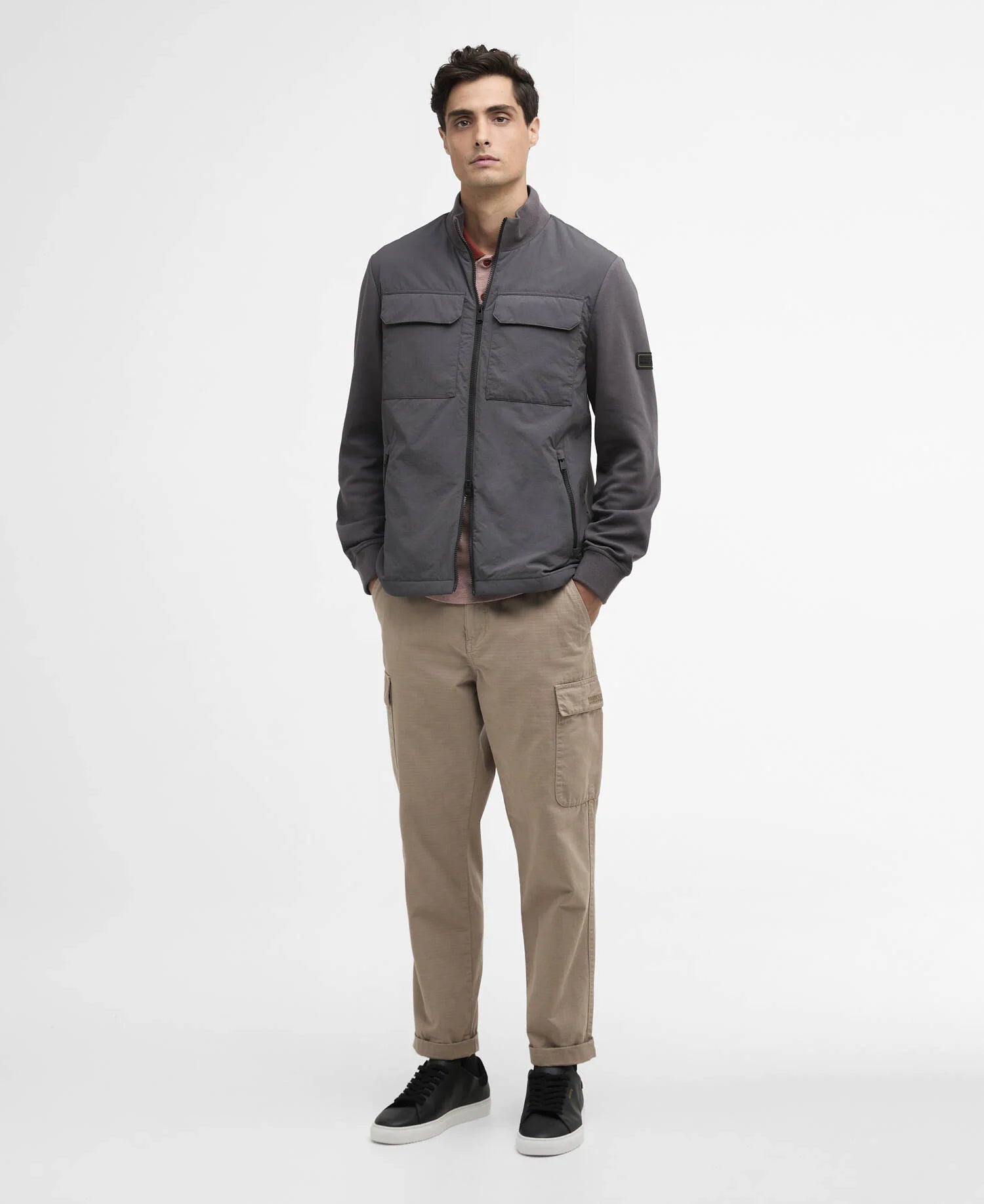 Man wearing a gray jacket and beige pants on a white background