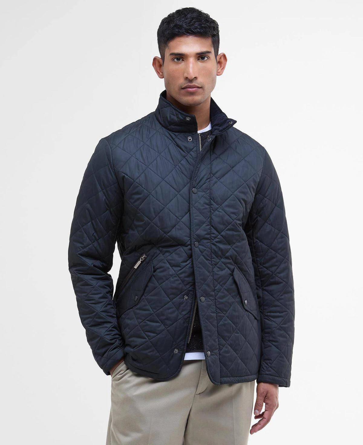 Man wearing a quilted navy jacket on a white background