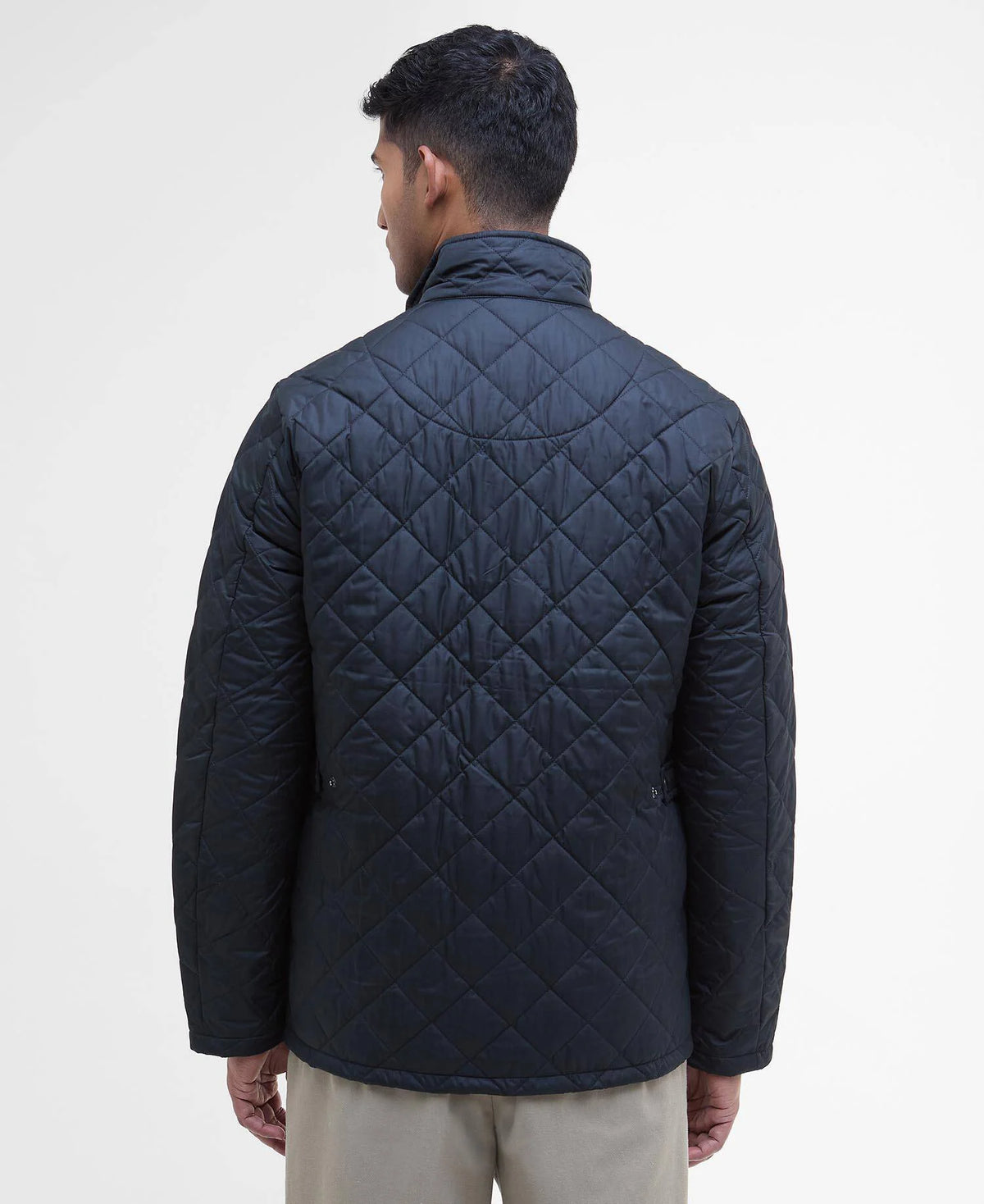 Man wearing a quilted navy jacket on a white background
