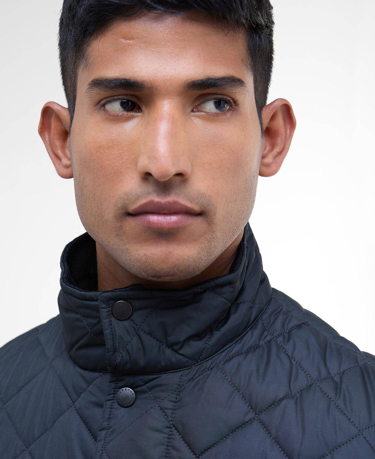 Close up of a man wearing a quilted navy jacket with the buttons fastened