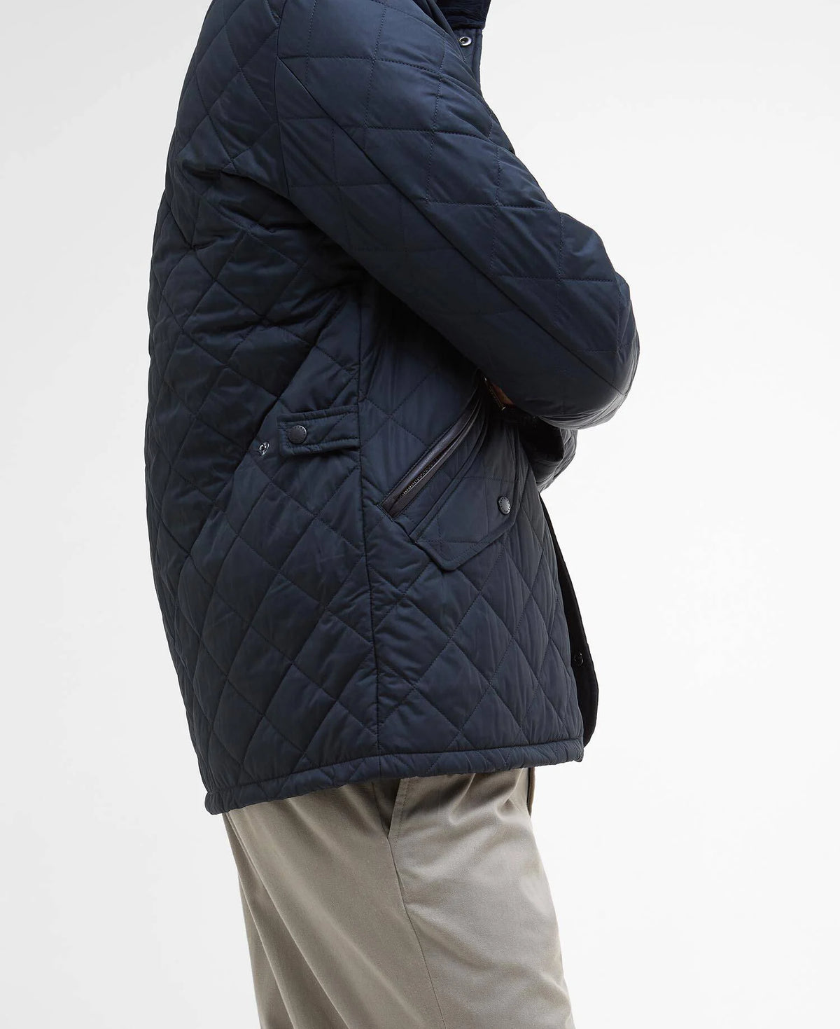 Man wearing a quilted navy jacket and grey chinos on a grey background