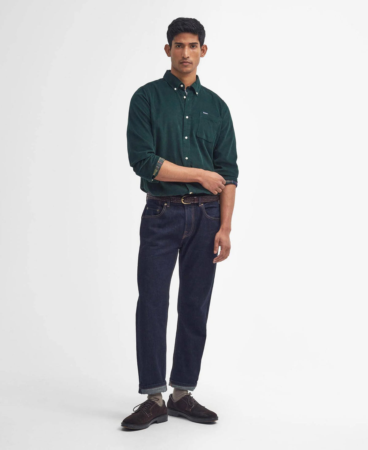 Man wearing a green shirt and dark jeans on a white background