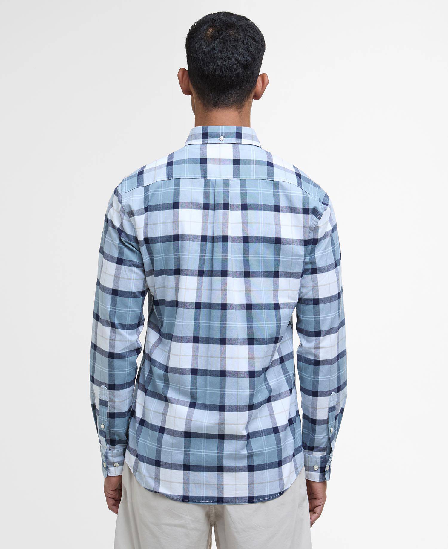Man wearing a blue and white checkered shirt on a plain background