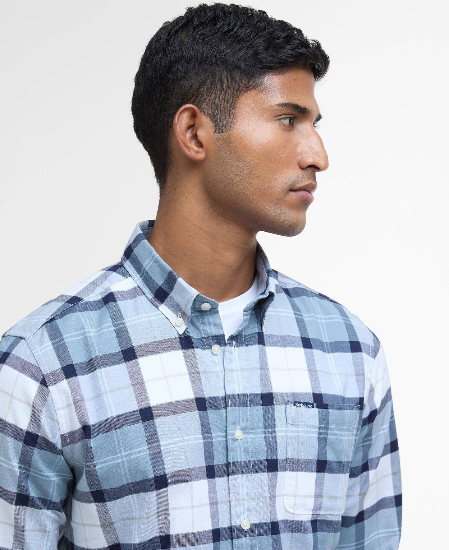 Man wearing a blue and white checkered shirt against a plain background