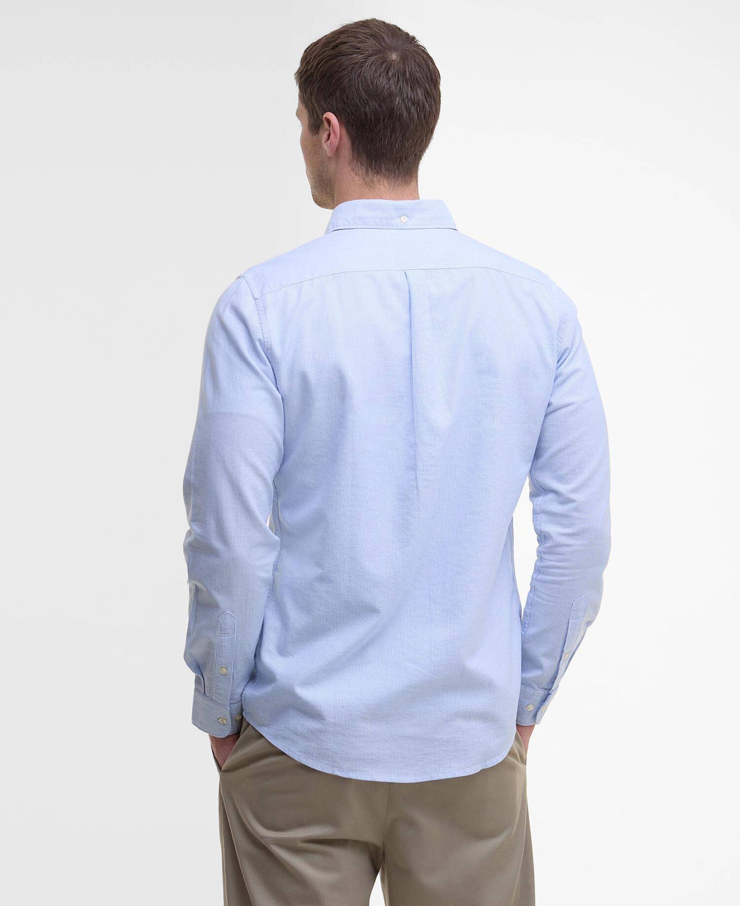 Man wearing a light blue shirt and beige pants on a white background